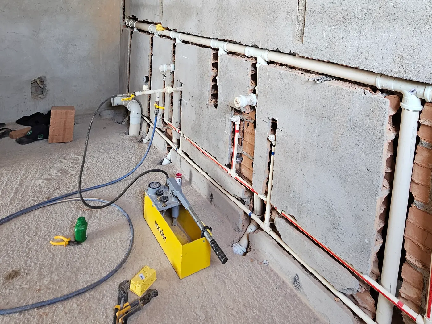 Vários ramais de tubulação hidráulica conectados à bomba de teste de pressão, obra do Residencial San Vitale